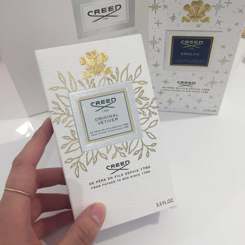 Creed perfume box on display with gold hand drawn floral design around the logo