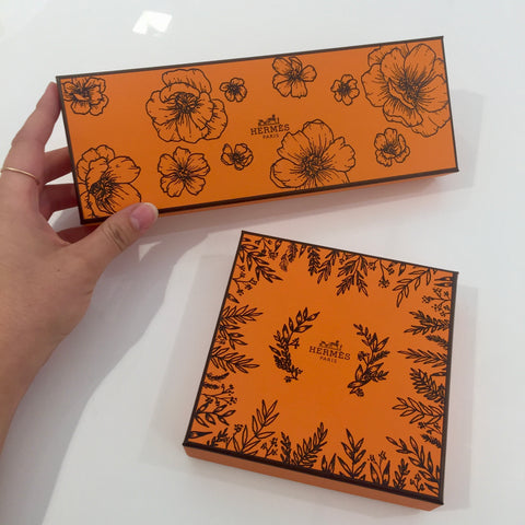 Two custom decorated orange Hermès Paris boxes are sitting on a white surface. 