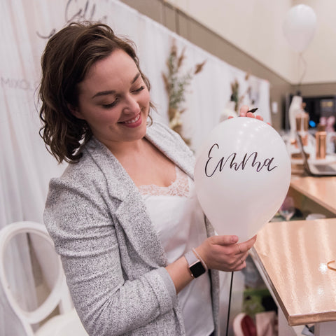 Mabz holds a white balloon with the name Emma written in modern calligraphy.