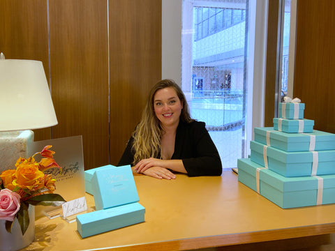 Chalked by Mabz sits behind a desk at Tiffany & Co. in the Rideau Centre in Ottawa, Ontario. Mabz is surrounded by customized Tiffany blue gift boxes.